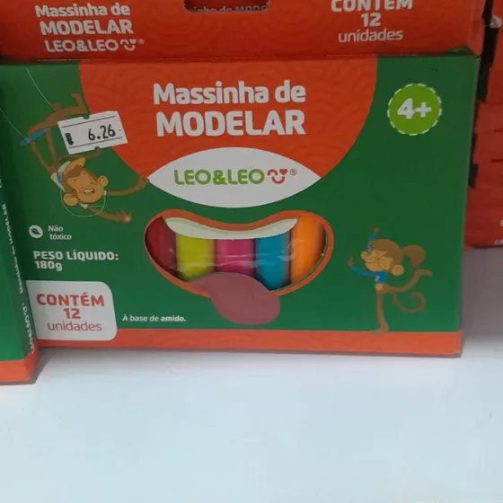 A foto original enviada pelo lojista: a caixa de massinha de modelar na prateleira do mercado, fotografada de celular, com a etiqueta de preço colada.